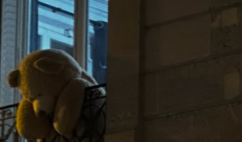 A teddy bear left on a balcony railing