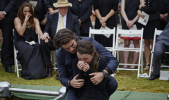 Two grieving people embracing at a funeral