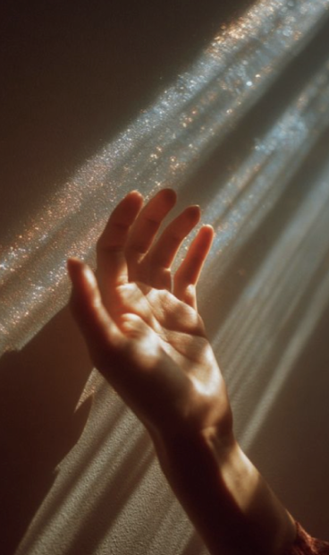 Hand reaching into warm rays of light