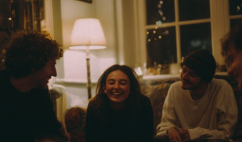 A small group of friends laughing together in a warmly-lit living room